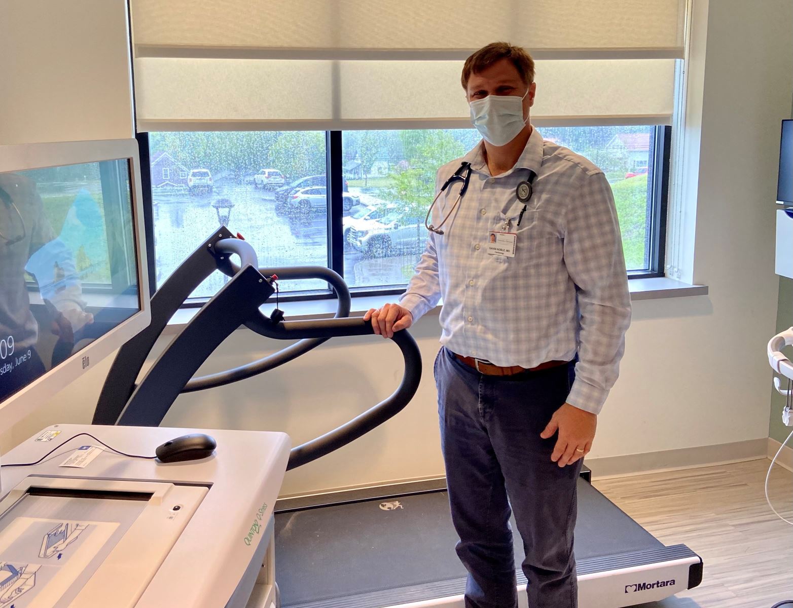 Dr. Gavin Noble stands next to a new treadmill 