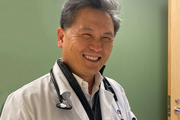 Jun Chon, MD, Primary Care Physician smiling with green background